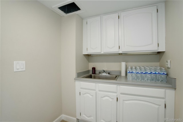 bar with white cabinetry and sink