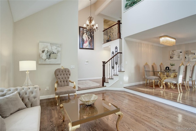 living room with hardwood / wood-style flooring, crown molding, high vaulted ceiling, and a chandelier