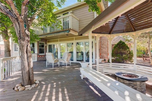 exterior space with a wooden deck, a balcony, a gazebo, and an outdoor fire pit