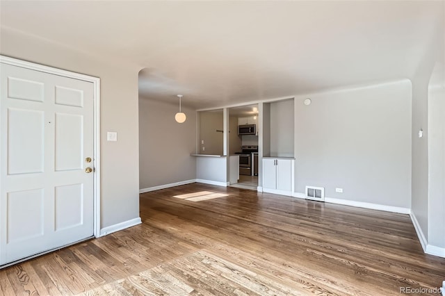 3075 Fairfax St, Denver, CO 80207 - unfurnished living room with baseboards, wood finished floors, visible vents, and arched walkways