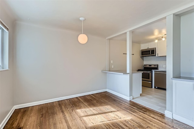 3075 Fairfax St, Denver, CO 80207 - kitchen with white cabinets, stainless steel appliances, decorative backsplash, and light wood finished floors