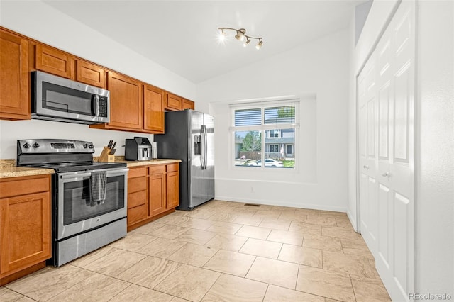 878 Candlestar Loop, Fountain, CO 80817 - kitchen featuring stainless steel appliances, vaulted ceiling, light countertops, brown cabinetry, and baseboards