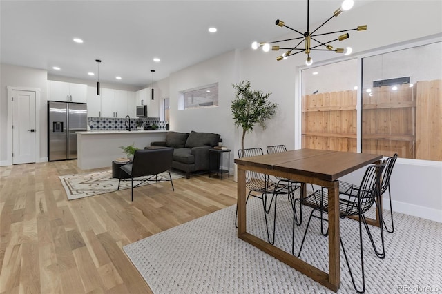 dining room with light wood-type flooring and a notable chandelier