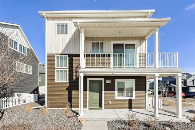 view of front of house featuring a balcony and fence