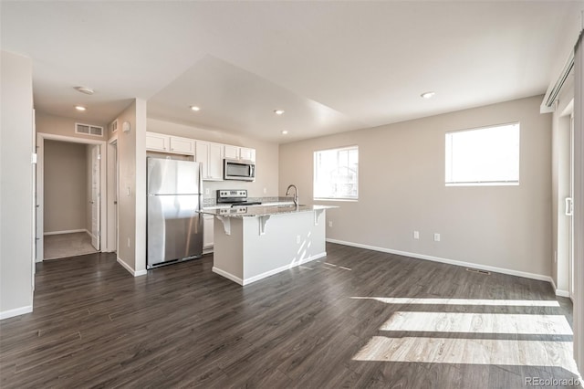 kitchen with dark wood finished floors, a breakfast bar area, visible vents, and appliances with stainless steel finishes