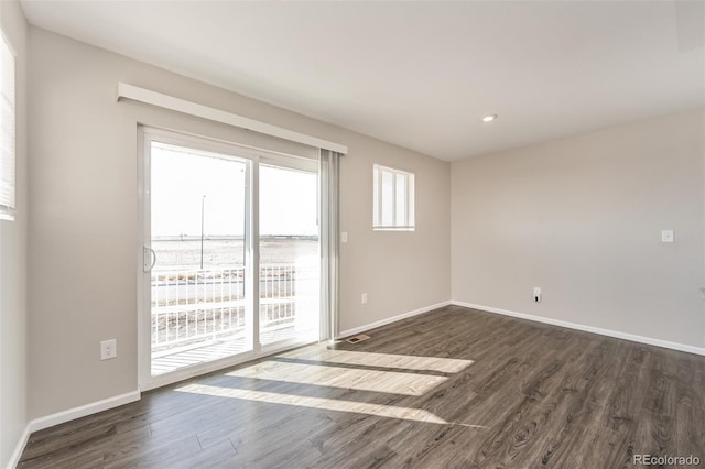 empty room featuring baseboards and dark wood-style flooring