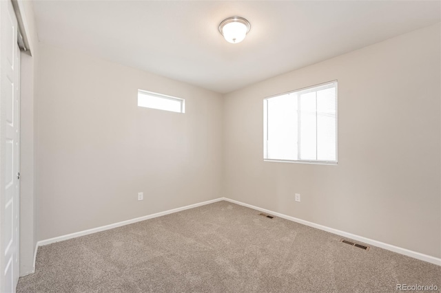 carpeted empty room featuring visible vents and baseboards