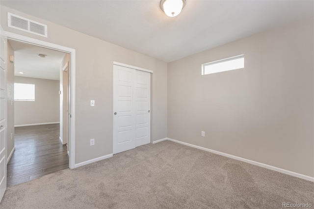 unfurnished bedroom with a closet, visible vents, carpet flooring, and baseboards