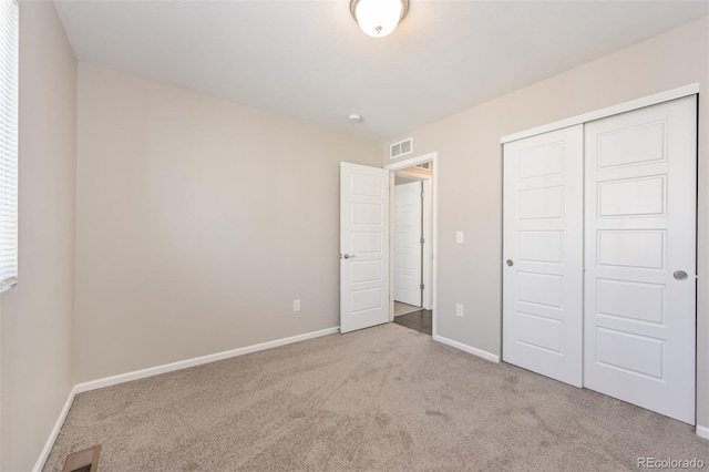 unfurnished bedroom with carpet flooring, baseboards, visible vents, and a closet