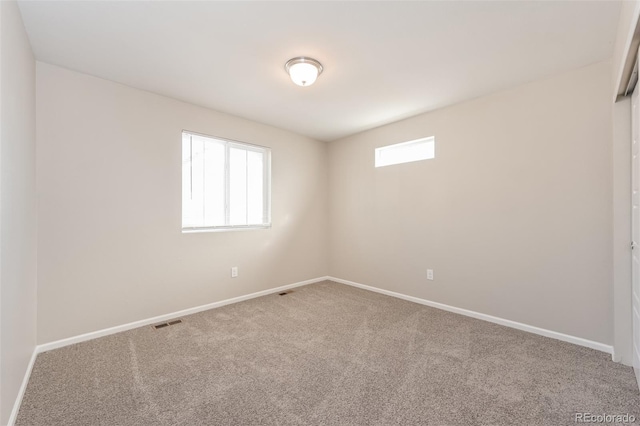 unfurnished room featuring carpet flooring, visible vents, and baseboards