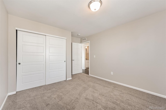 unfurnished bedroom featuring carpet, visible vents, a closet, and baseboards