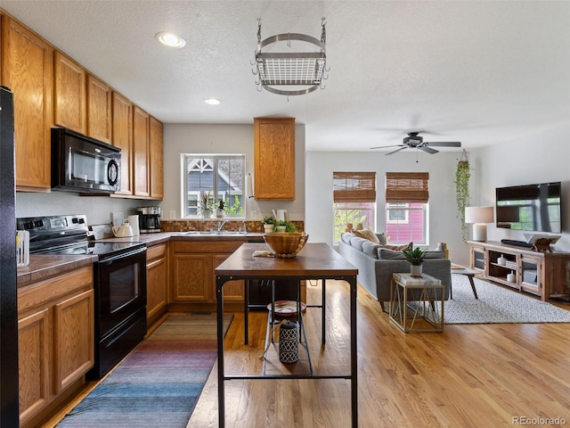 kitchen with ceiling fan, sink, a textured ceiling, black appliances, and light hardwood / wood-style floors