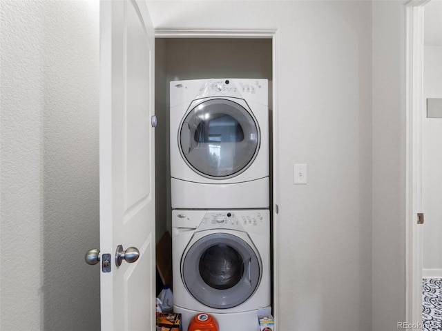 clothes washing area featuring stacked washing maching and dryer