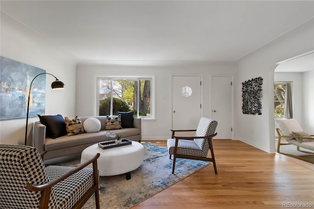 living room with arched walkways and light wood-style flooring