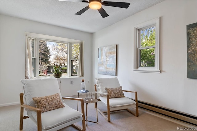 living area featuring a baseboard radiator, baseboards, ceiling fan, and carpet