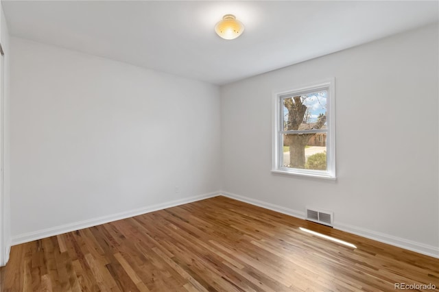 empty room featuring visible vents, baseboards, and wood finished floors