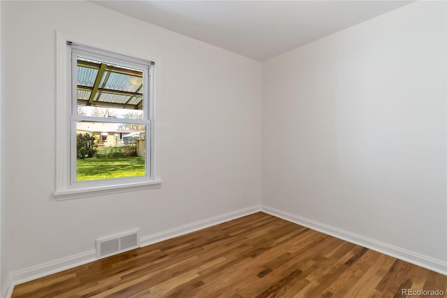 unfurnished room featuring baseboards, visible vents, and wood finished floors