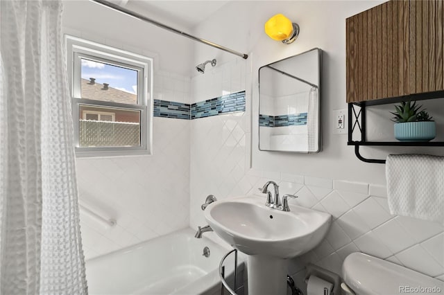 bathroom with toilet, tile walls, a sink, and shower / bath combo