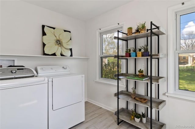 clothes washing area with baseboards, laundry area, light wood-style flooring, and washer and dryer