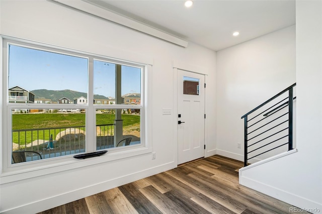 foyer featuring dark wood-type flooring, a mountain view, stairway, and baseboards