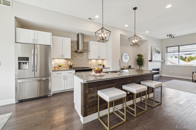 kitchen featuring a kitchen island with sink, sink, stainless steel fridge, dark hardwood / wood-style floors, and wall chimney range hood