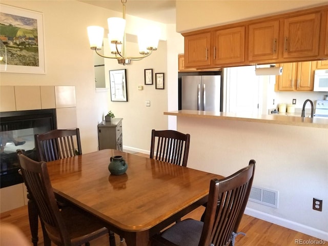 2240 S Pagosa Ct Unit B, Aurora, CO 80013 - dining room featuring a chandelier, light wood-style floors, baseboards, and a tiled fireplace