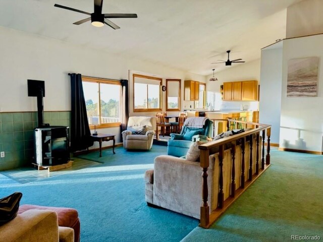 carpeted living room featuring a wood stove, ceiling fan, and lofted ceiling