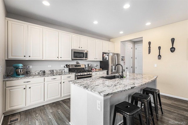 kitchen with sink, white cabinetry, a center island with sink, appliances with stainless steel finishes, and a kitchen breakfast bar