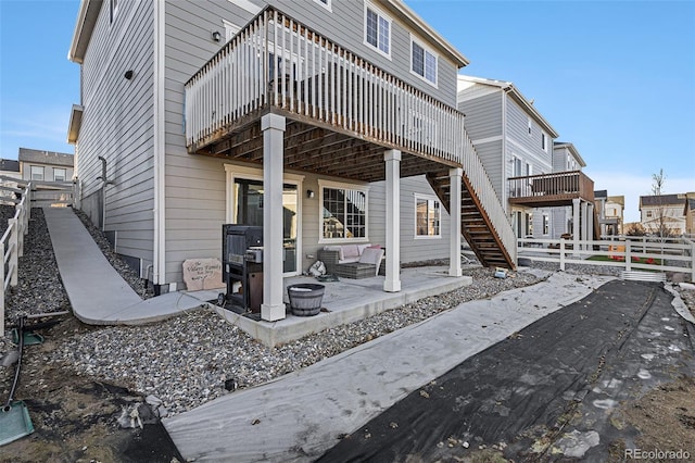 rear view of property with a wooden deck, a patio area, and an outdoor fire pit