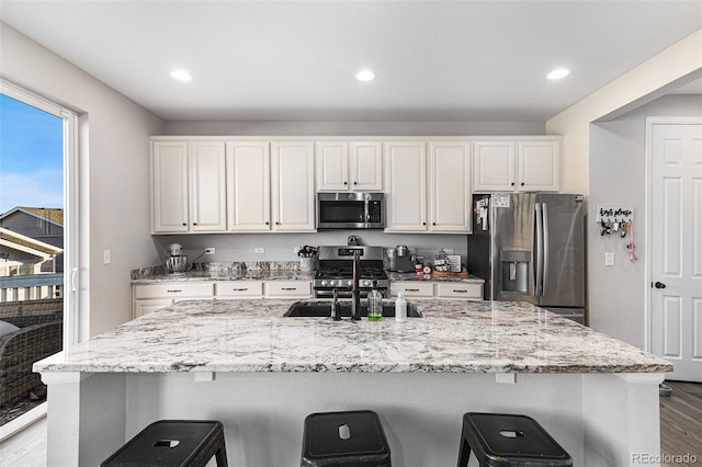 kitchen with white cabinetry, appliances with stainless steel finishes, a kitchen breakfast bar, and sink