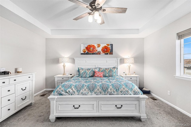 carpeted bedroom featuring a raised ceiling and ceiling fan