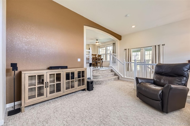 living room with carpet floors, arched walkways, ceiling fan, and lofted ceiling