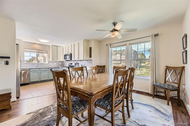 dining space featuring ceiling fan, baseboards, and light wood-style floors