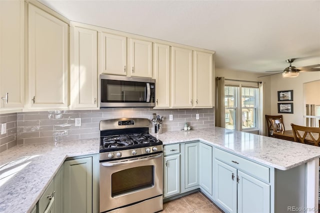 kitchen featuring stainless steel appliances, a ceiling fan, decorative backsplash, and a peninsula