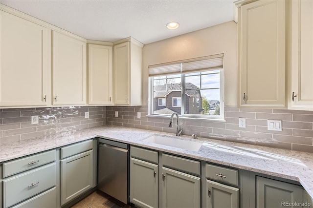 kitchen featuring stainless steel dishwasher, a sink, decorative backsplash, and light stone countertops