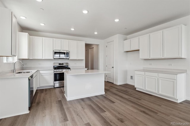 19100 E 96th Pl, Commerce City, CO 80022 - kitchen with appliances with stainless steel finishes, a sink, wood finished floors, white cabinets, and a center island