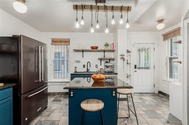 2719 W 32nd Ave, Denver, CO 80211 - kitchen with high end fridge, blue cabinets, stone tile floors, a kitchen island, and tasteful backsplash