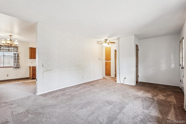 carpeted spare room with ceiling fan with notable chandelier and a textured ceiling