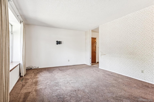 empty room with carpet and a textured ceiling