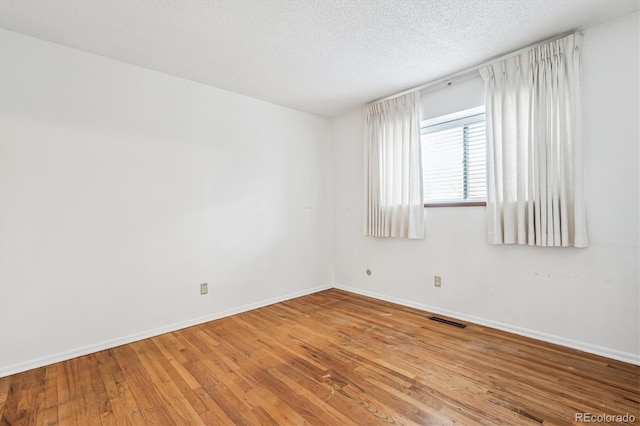 unfurnished room featuring a textured ceiling and light hardwood / wood-style flooring