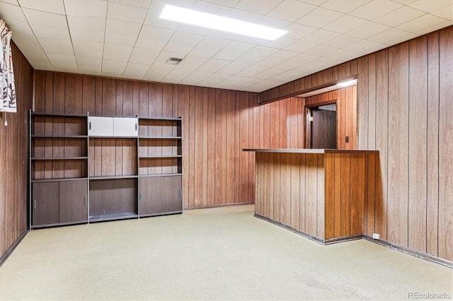 interior space with bar area, wooden walls, and light colored carpet