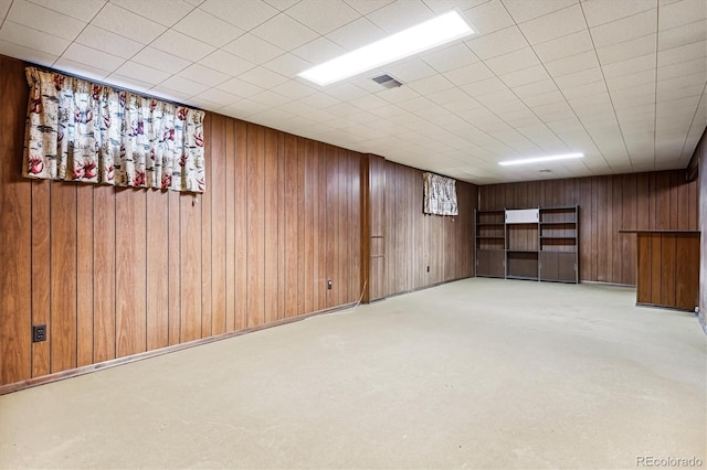 basement with light carpet and wooden walls