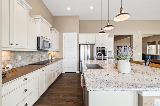 kitchen with pendant lighting, white cabinetry, sink, stainless steel appliances, and a spacious island