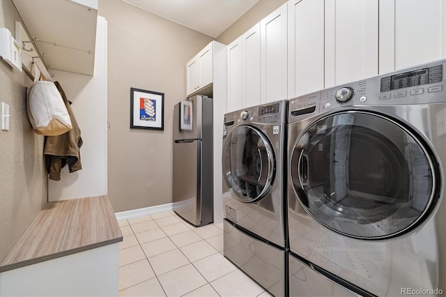 clothes washing area with cabinets, separate washer and dryer, and light tile patterned floors