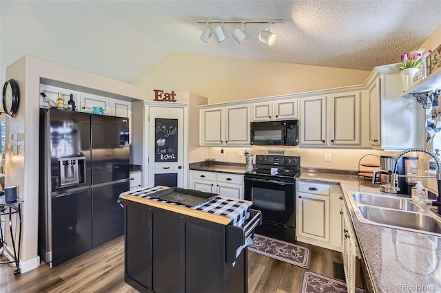 2251 W 135th Pl, Denver, CO 80234 - kitchen with black appliances, lofted ceiling, wood finished floors, a center island, and rail lighting