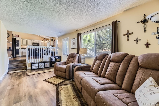 2251 W 135th Pl, Denver, CO 80234 - living room featuring a textured ceiling, light wood-style flooring, and a chandelier