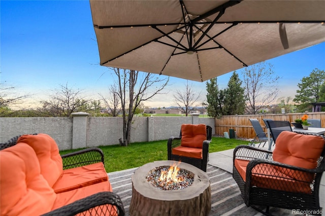 view of patio / terrace featuring a fenced backyard, outdoor dining space, and an outdoor fire pit