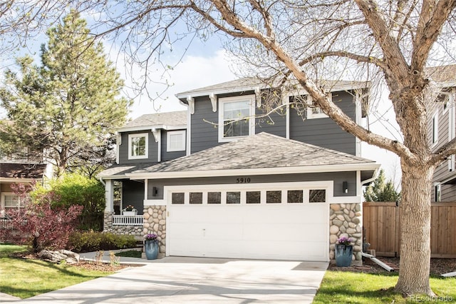 view of front of home with roof with shingles, fence, stone siding, a garage, and driveway