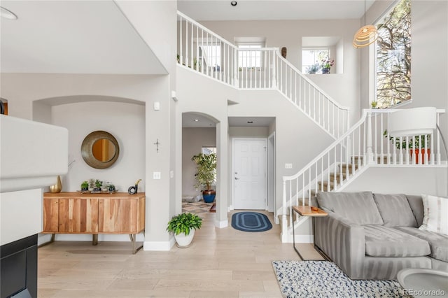 living area with baseboards, arched walkways, wood finished floors, and stairway