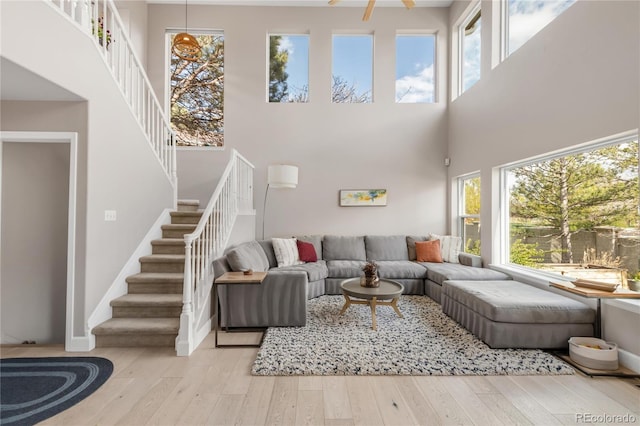 living room featuring wood-type flooring, baseboards, a towering ceiling, and stairway